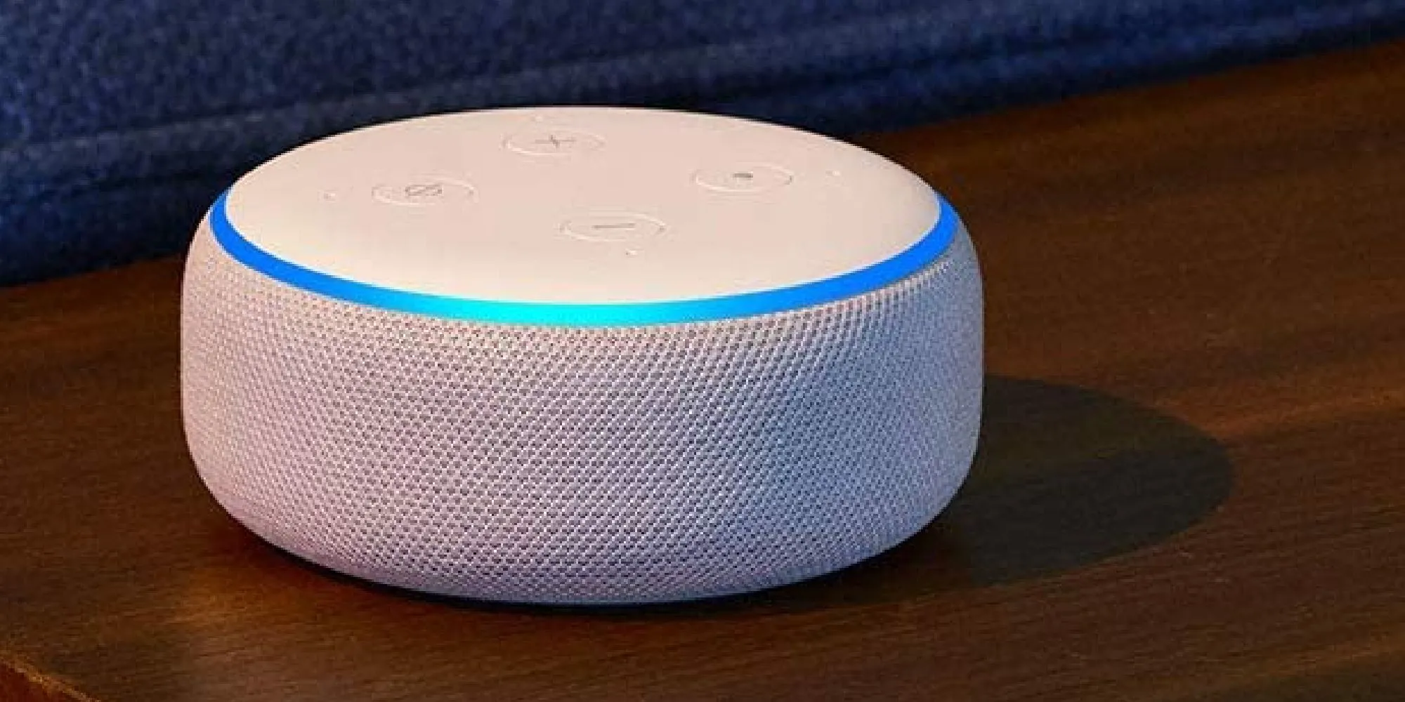 Thiết bị Amazon Alexa màu trắng đặt trên bề mặt gỗ, minh họa ý tưởng trợ lý ảo &quot;gamer&quot; với giọng điệu và phản hồi hài hước, cá tính của cộng đồng game thủ.