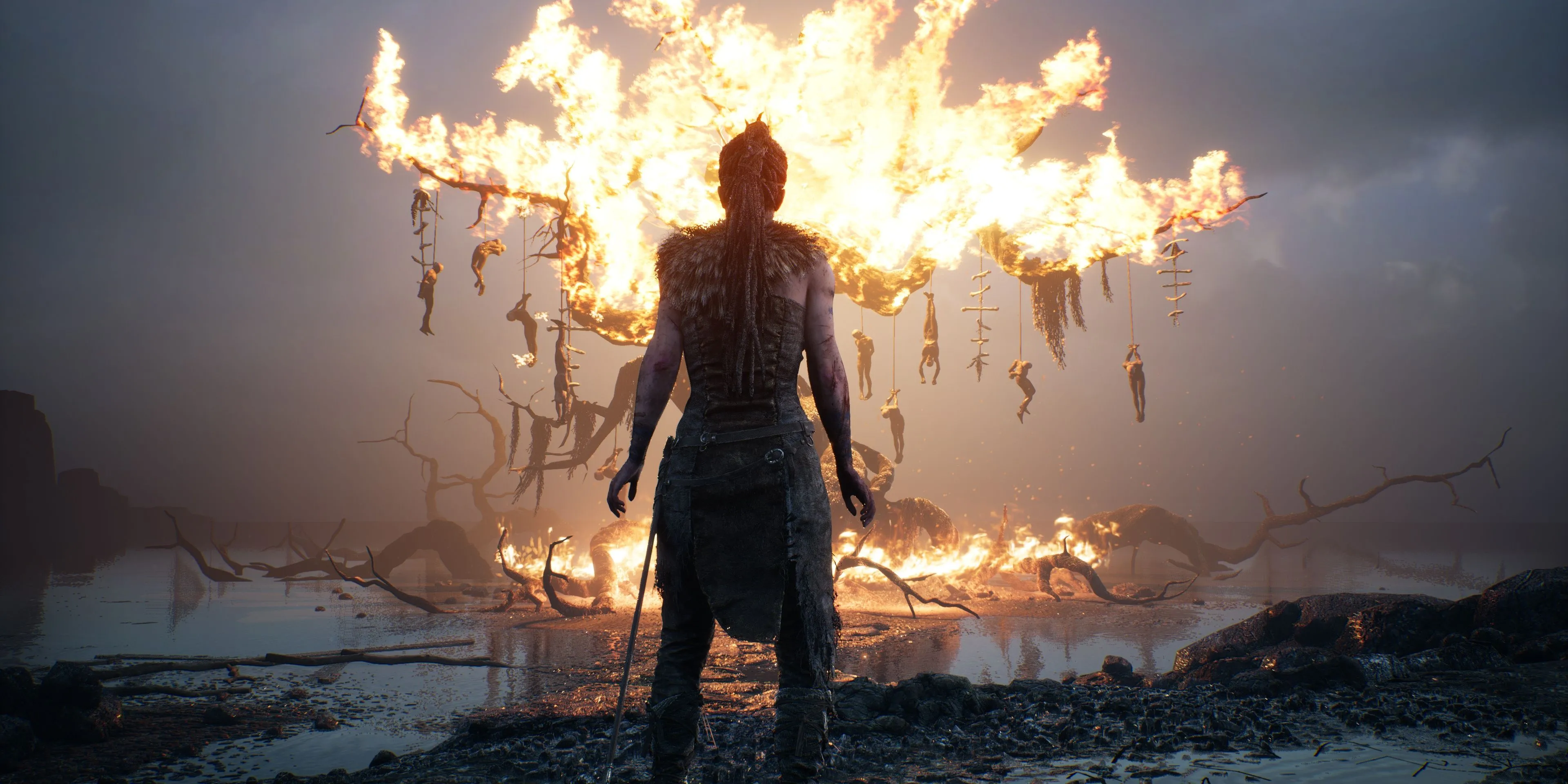 Hellblade: Senua's Sacrifice - Senua đứng trước một cái cây bốc cháy, biểu tượng cho cuộc chiến nội tâm của cô