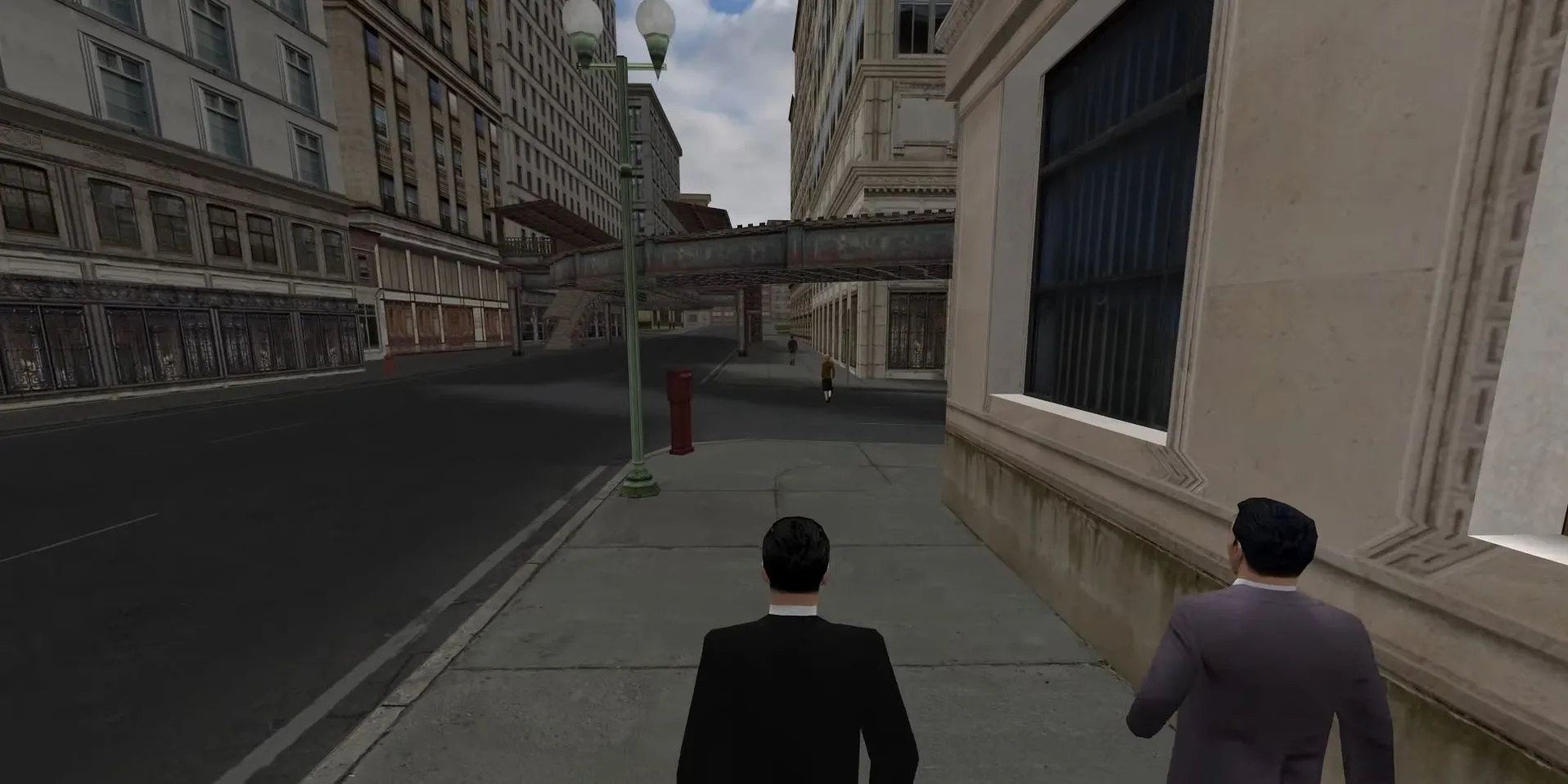 Hai người đàn ông trong trang phục thập niên 30 đi bộ trên đường phố của Mafia: Definitive Edition, tái hiện bầu không khí cổ điển